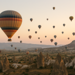 Hot air balloons gently rise over Cappadocia’s unique landscape at sunrise, offering a peaceful and scenic moment typical of a Cappadocia hot air balloon holiday.